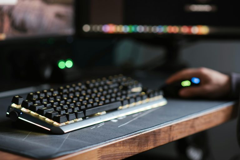 A modern workspace setup featuring a mechanical keyboard and mouse on a desk, backlit for a soft, ambient glow.