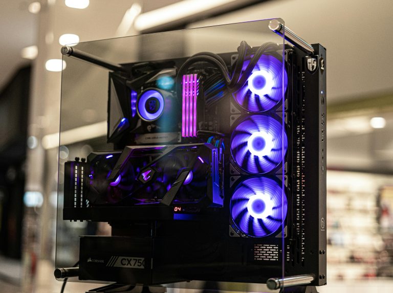 Modern gaming computer with vibrant LED fans and sleek glass design, showcasing high-performance components.